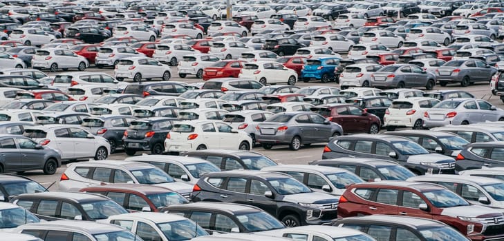 Lamchabang, Thailand - July 02, 2023 A distribution center in a sunny car factory houses rows of new cars. A top view reveals a bustling parking lota symbol of modern manufacturing and technology.