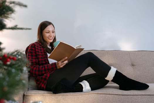 Caucasian woman reading book and relaxation on couch on Christmas holiday.