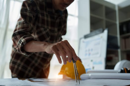 multi ethnic engineer brainstorming and measuring for cost estimating on blueprint and floor plan drawings about design architectural and engineering for houses and buildings.