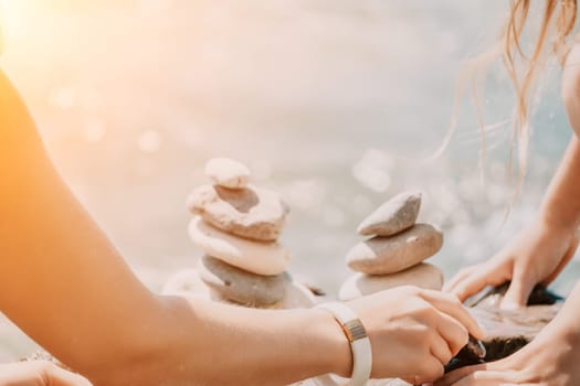 Balanced Pebbles Pyramid on the Beach on Sunny Day and Clear Sky at Sunset. Blue Sea on Background Selective focus, zen stones on sea beach, meditation, spa, harmony, calm, balance concept.