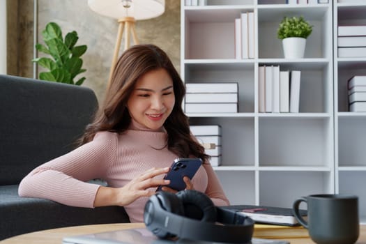 Happy girl checking social media holding smartphone sitting at sofa in living room at home. relaxing concepts