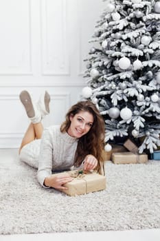 woman decorating christmas tree with gifts for new year