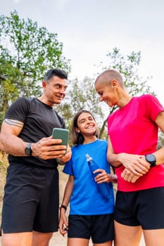 sporty family using a mobile phone and smart watch to plan their sports training in the countryside, concept of sport with kids in nature and active lifestyle, copy space for text