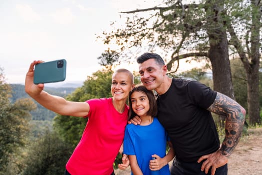 happy sporty family taking a selfie photo in the nature with mobile phone, concept of outdoor activities with children and healthy lifestyle, copy space for text