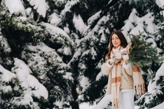 A girl in a winter forest with a bouquet of fir branches. Snowy winter.