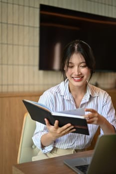 Portrait of successful young businesswoman checking working schedule plan at desk.