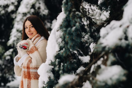 Portrait of a girl with long hair in mittens in a winter forest . Snowy winter.