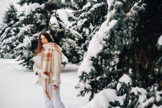 Portrait of a girl with long hair in mittens in a winter forest . Snowy winter.