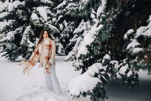 Portrait of a girl with long hair in mittens in a winter forest . Snowy winter.