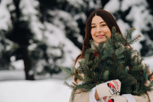 A girl in a winter forest with a bouquet of fir branches. Snowy winter.