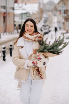 A girl with long hair in winter on the street with a bouquet of fresh fir branches.