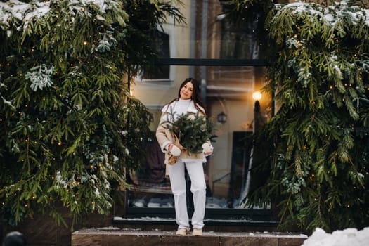 A girl with long hair in winter on the street with a bouquet of fresh fir branches.