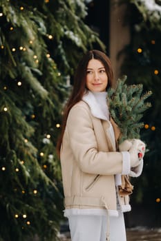 A girl with long hair in winter on the street with a bouquet of fresh fir branches.