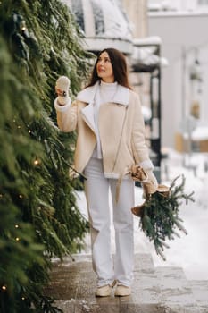 A girl with long hair in winter on the street with a bouquet of fresh fir branches.