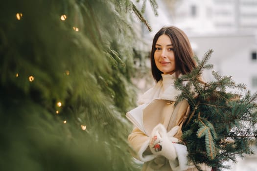 A girl with long hair in winter on the street with a bouquet of fresh fir branches.