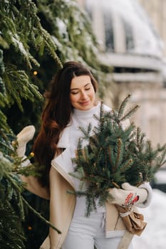 A girl with long hair in winter on the street with a bouquet of fresh fir branches.