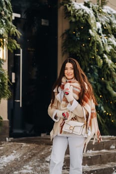 A girl with long hair in a scarf and with a white handbag walks down the street in winter.