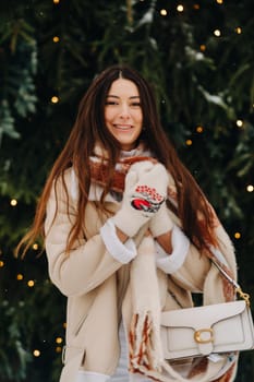 A girl with long hair in a scarf and with a white handbag walks down the street in winter.