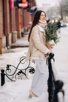 Girl with long hair in winter on the street with a bouquet of fresh spruce branches.
