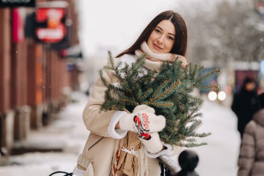 Girl with long hair in winter on the street with a bouquet of fresh spruce branches.