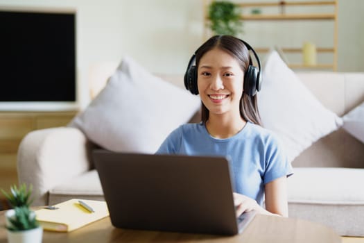 woman wearing headphones on comfortable couch listening to using computer laptop and music