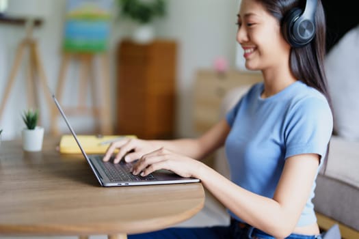 woman wearing headphones on comfortable couch listening to using computer laptop and music