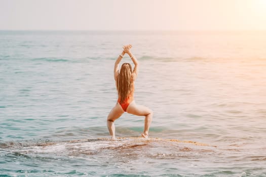 Woman sea yoga. Back view of free calm happy satisfied woman with long hair standing on top rock with yoga position against of sky by the sea. Healthy lifestyle outdoors in nature, fitness concept.