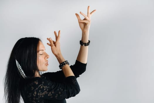 A girl in a black dress moves in a dance on a gray background. Dynamic dance,