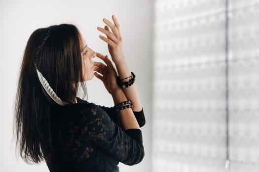 A girl in a black dress moves in a dance on a gray background. Dynamic dance,