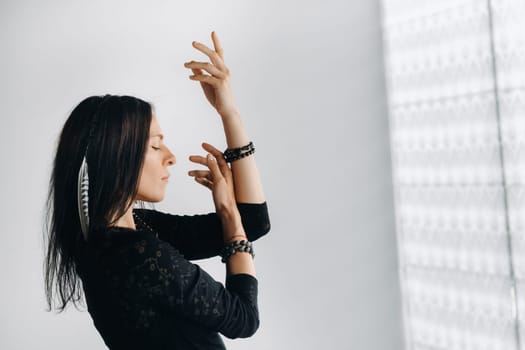 A girl in a black dress moves in a dance on a gray background. Dynamic dance,