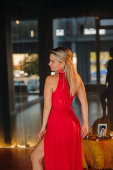 A girl in a red dress moves in a dance meditating indoors . Dynamic dance,