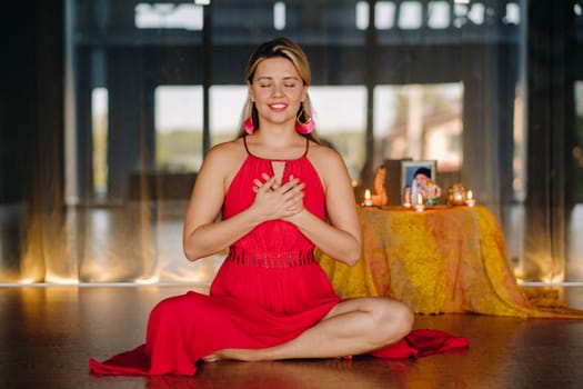 Meditation and concentration. a woman in a red dress sitting on the floor is practicing medicine indoors . Calm and relaxation.