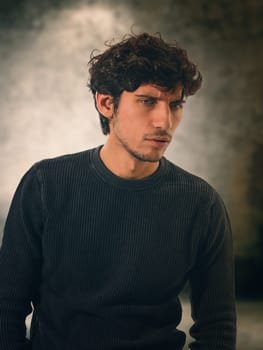 A man in a black sweater is posing with a tormented, worried expression, looking aodwn