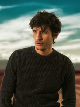 A man in a black sweater standing in a desert road, outdoor in a sunny day