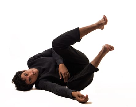 A young man laying, falling on the ground in a funny pose, looking at camera in studio shot isolated on white