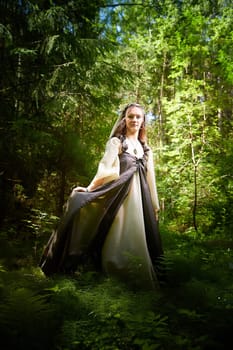 Beautiful seductive dryad. Pagan spirit of forest. Portrait of beautiful dryad. Fairy who loves nature in beautiful green summer forest. Concept of environmental friendliness and caring for nature