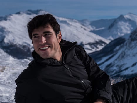 A man sitting on top of a snow covered mountain