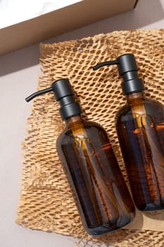 amber glass cosmetic bottles dispensers in box , unpacking eco friendly gift on earthy colored background