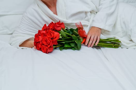 An elegant and luxurious scene of a beautiful woman reclining on a plush hotel bed, surrounded by a large bouquet of vibrant red roses, exuding a sense of relaxation and indulgence.
