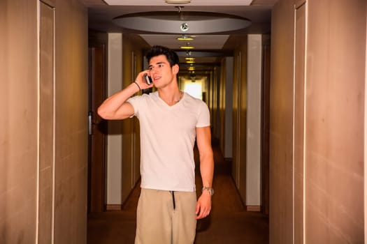 A man talking on a cell phone while standing in a hallway