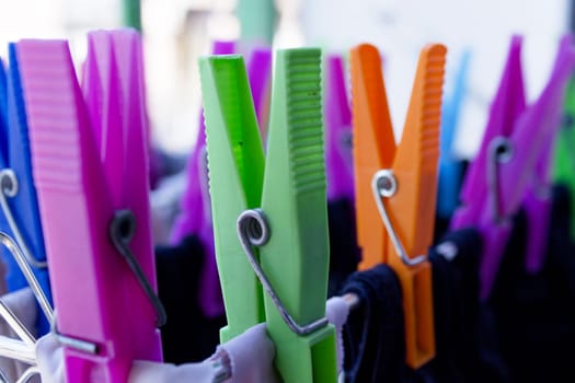 Clothespins holding clothes on clothesline. Various colors. No people