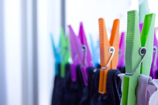 Clothespins holding clothes on clothesline. Various colors. No people