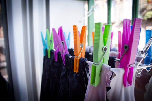 Clothespins holding clothes on clothesline. Various colors. No people