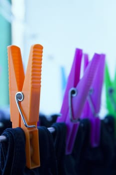 Clothespins holding clothes on clothesline. Various colors. No people