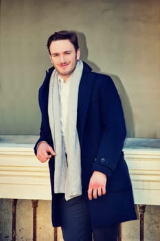 A man in a coat and scarf posing for a picture