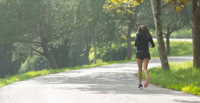 A woman running down a road in a park