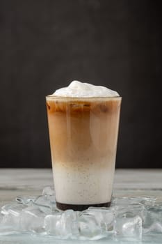 Multilayer iced coffee latte in glass cup on wooden table