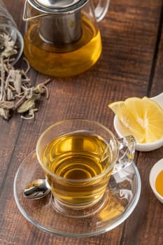 Dried sage tea in glass cup on wooden table