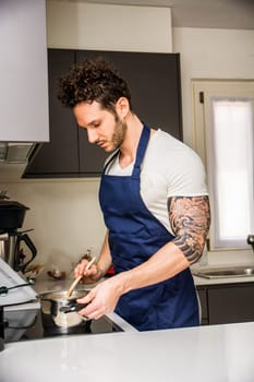 A man in an apron is cooking in a kitchen. A Skillful Chef Preparing a Delicious Meal in a Modern Kitchen