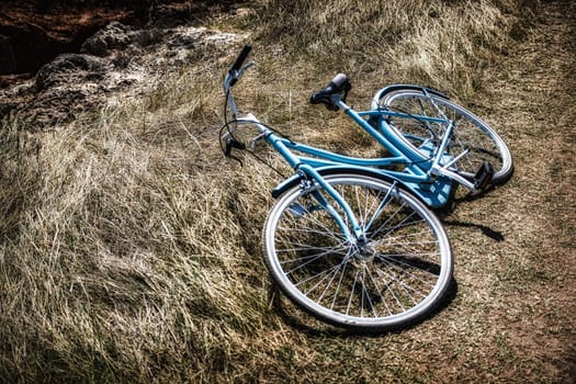 A blue bike laying on the ground in the grass